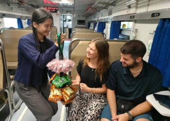 Seorang Pramugari Kereta menjajakan Jajanan dengan Nuansa Pedagang Asongan. Sumber: KAI